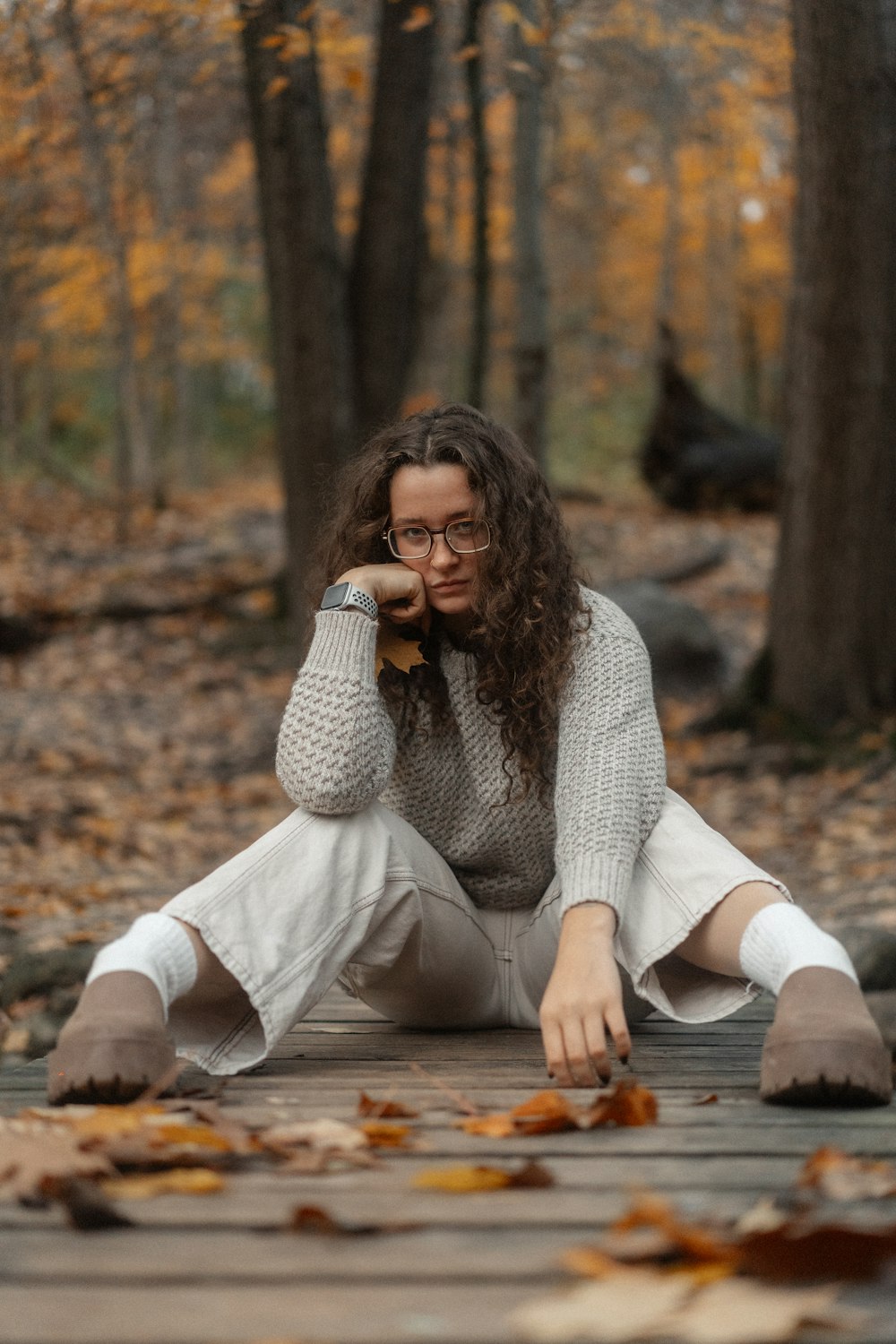a woman sitting on a wooden floor in the woods