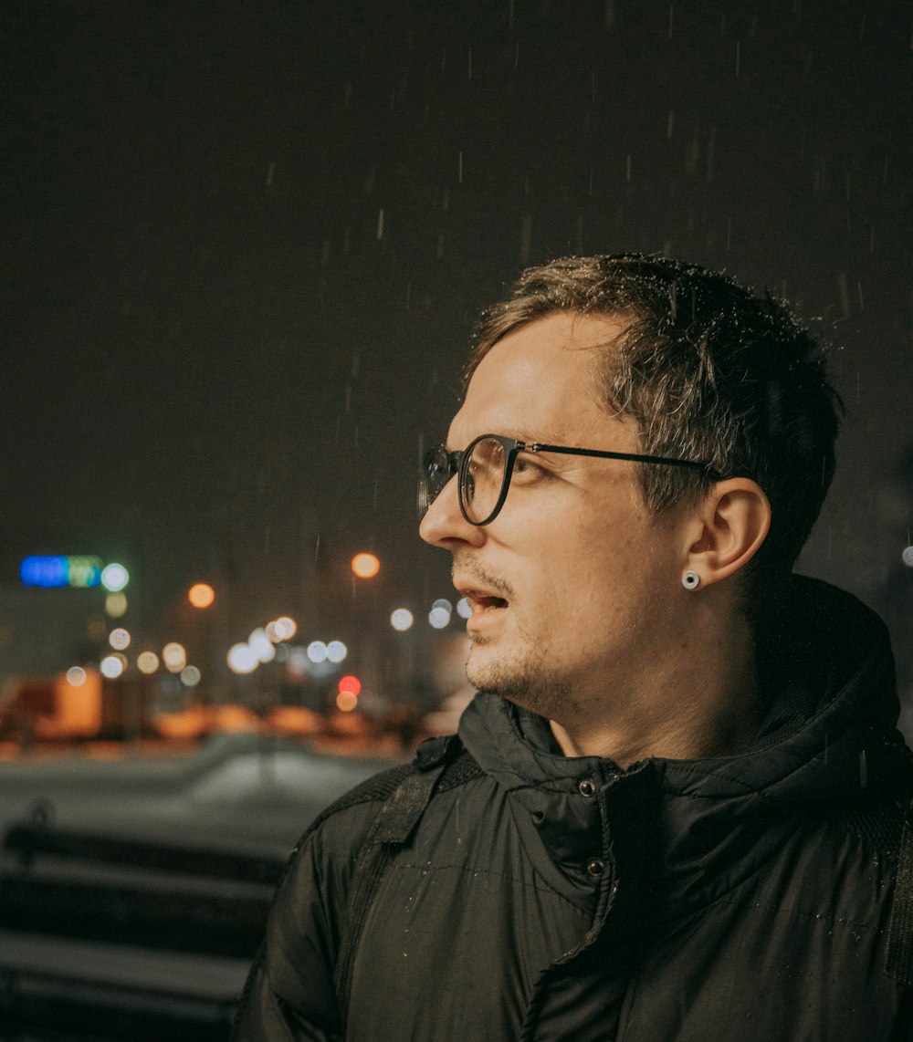 a man wearing glasses standing in the rain