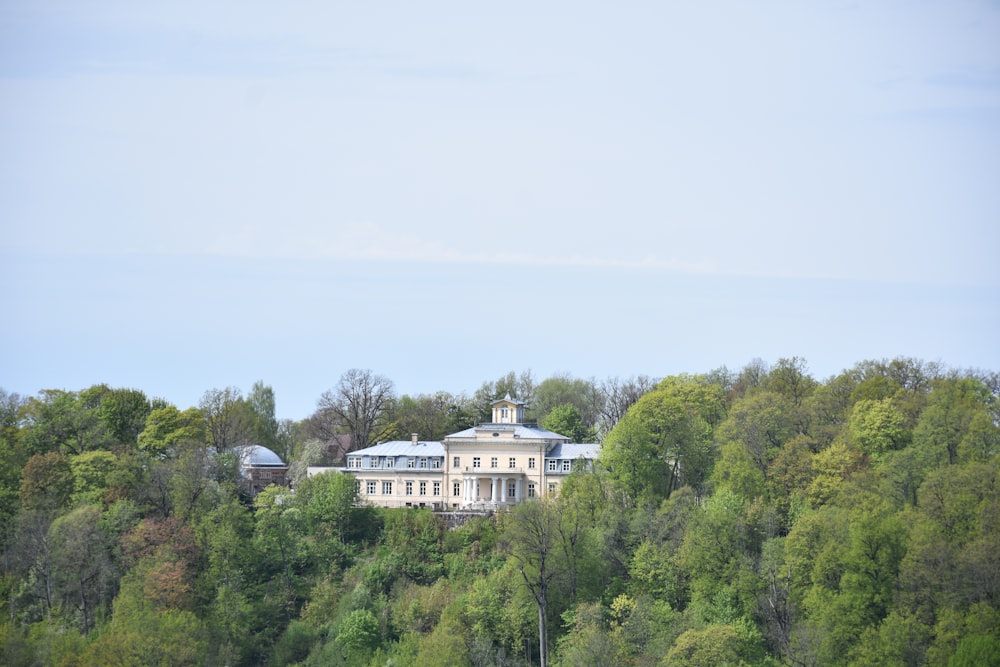 Una grande casa bianca seduta in cima a una collina verde lussureggiante