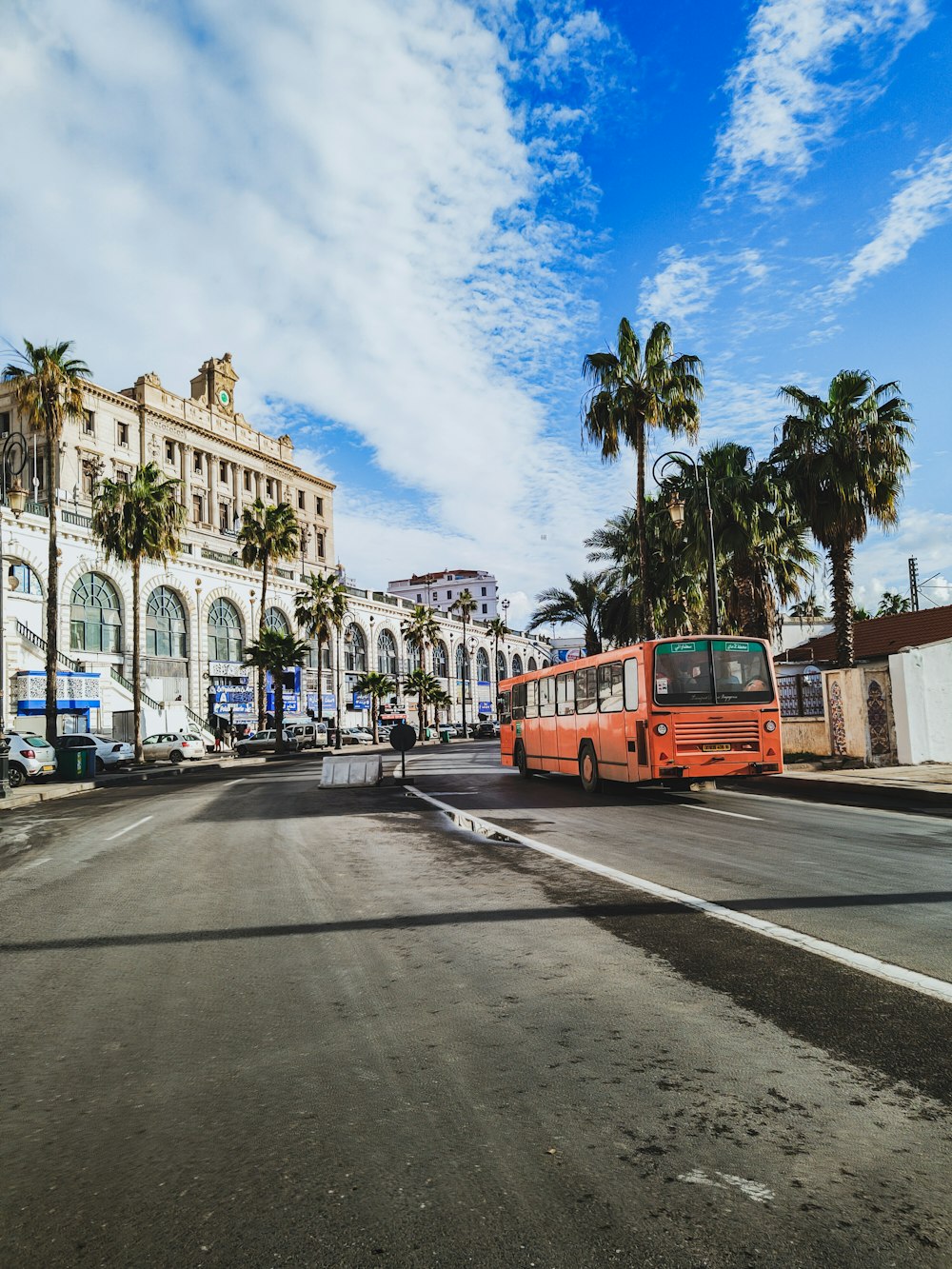 a red bus driving down a street next to tall buildings