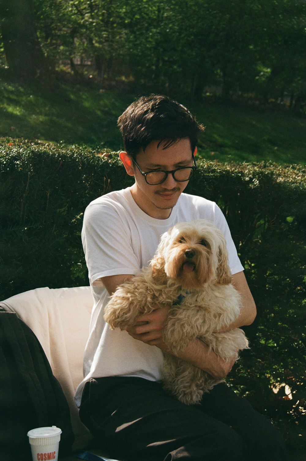 a man sitting on a bench holding a dog