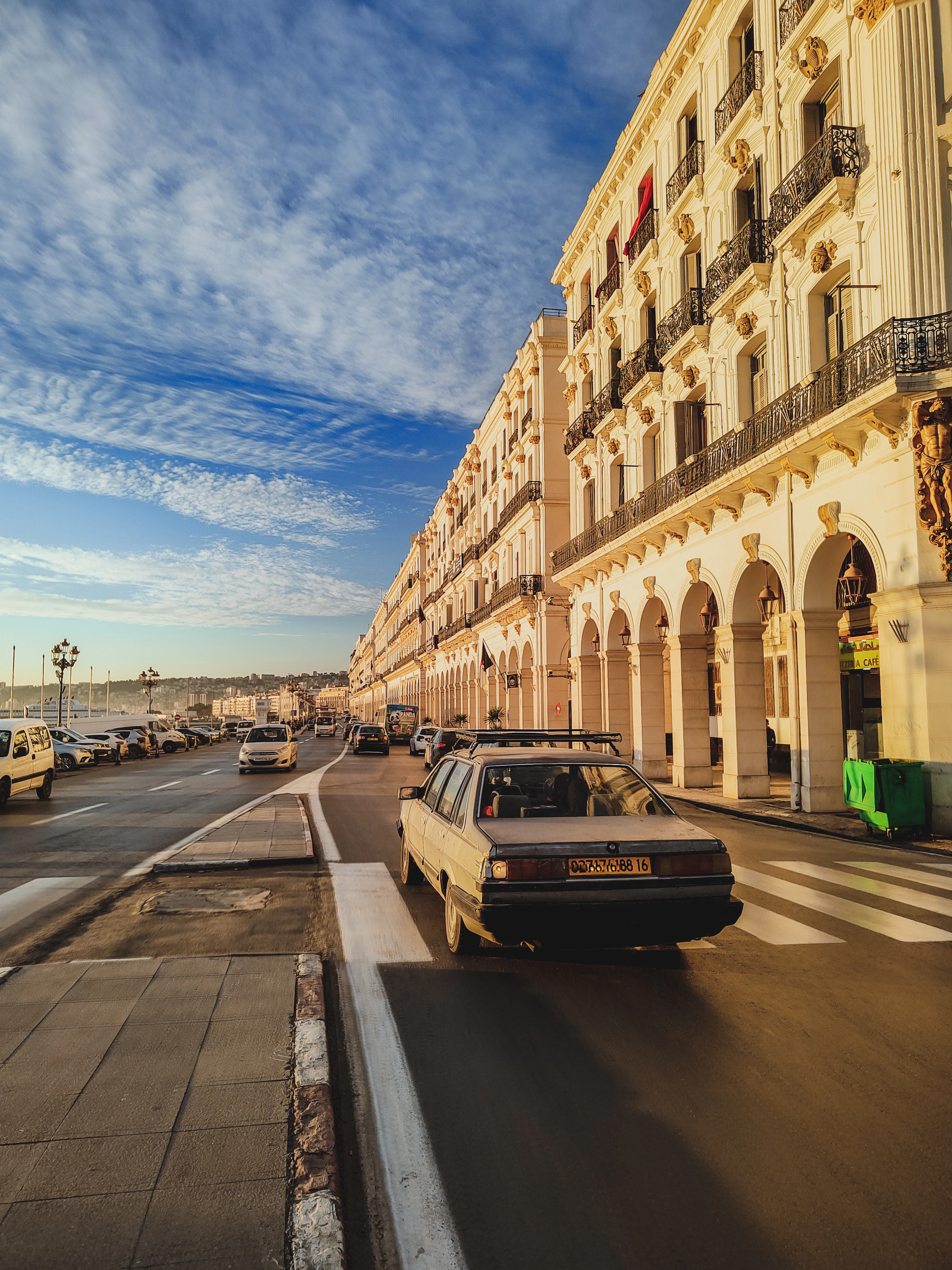 An arcaded boulevard of white colonial buildings in Algiers under a blue sky