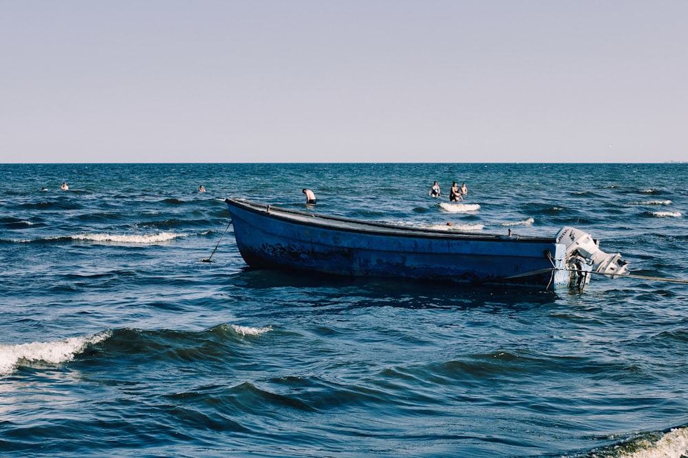 um pequeno barco azul no meio do oceano