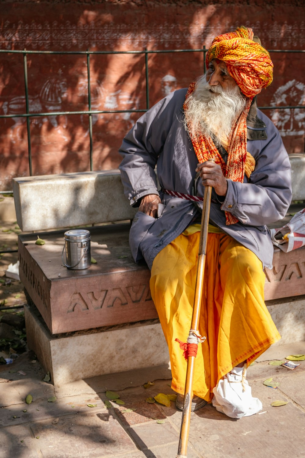 an old man sitting on a bench with a stick