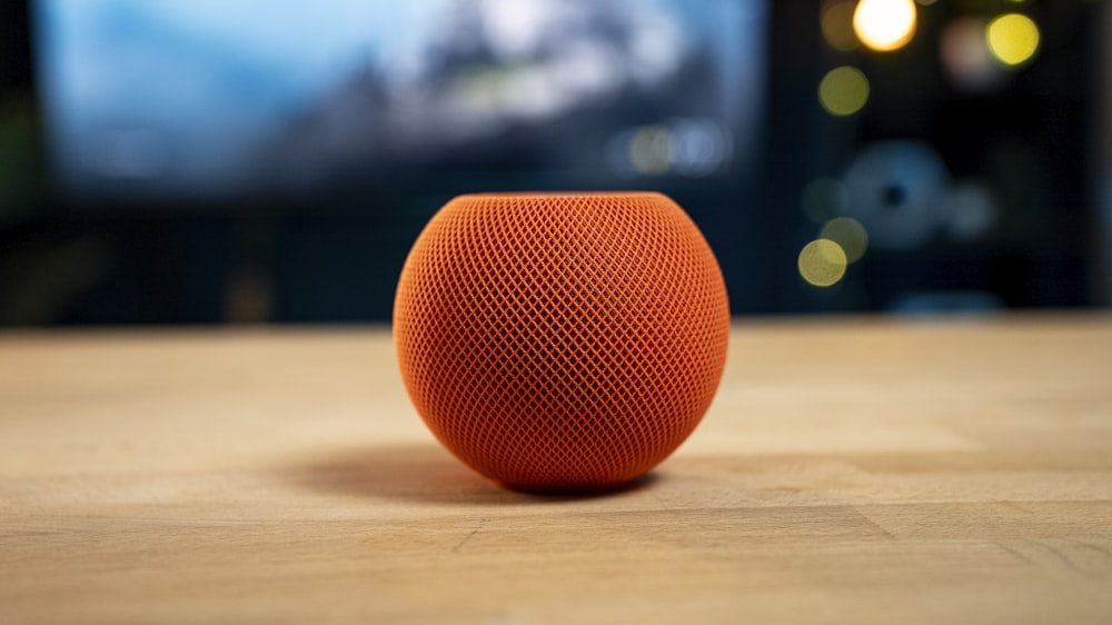 an orange speaker sitting on top of a wooden table