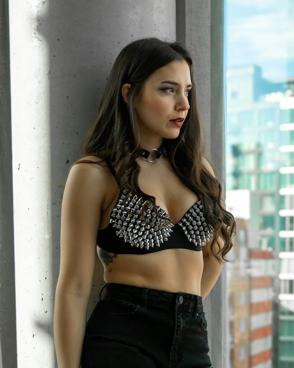 a woman in a black bra top leaning against a wall