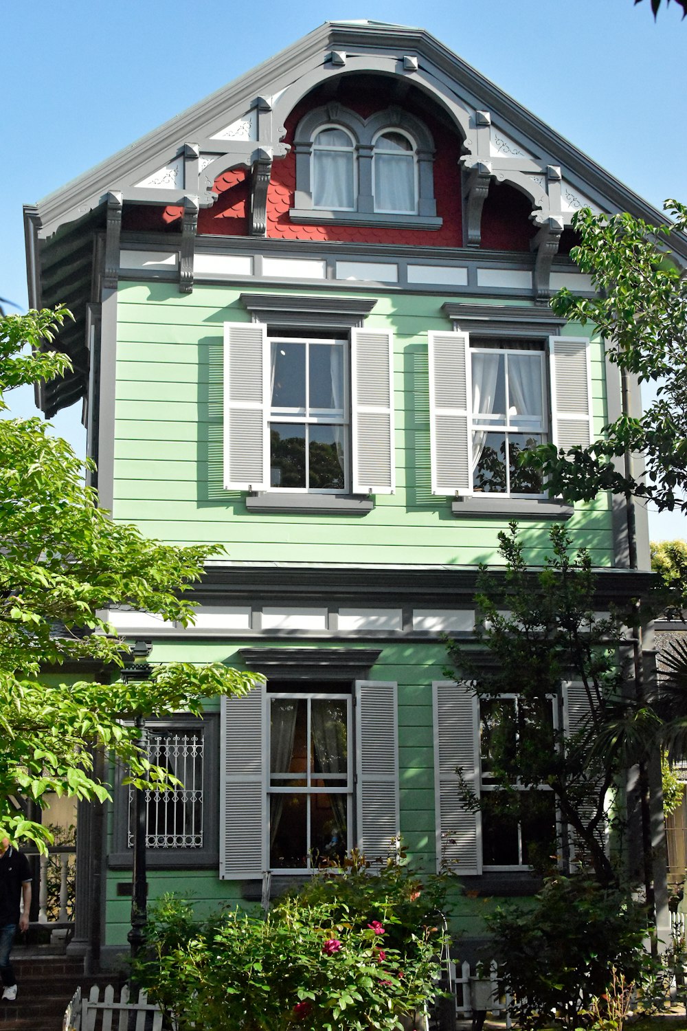 a green house with a red roof and white shutters