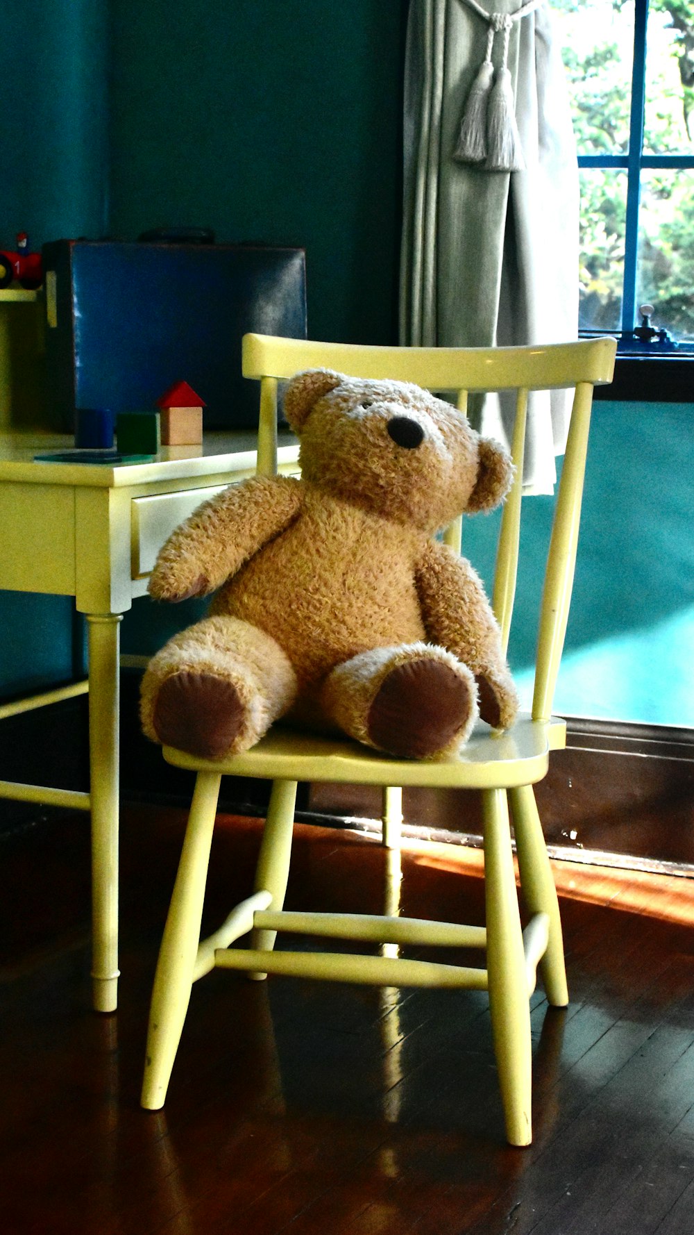 a brown teddy bear sitting in a yellow chair