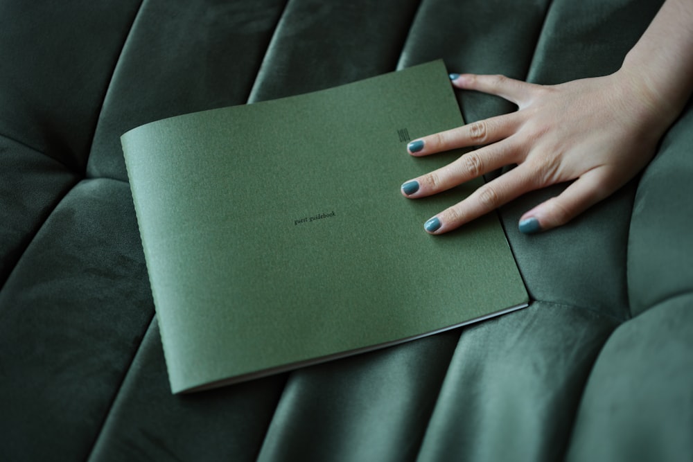 a woman's hand resting on a green book