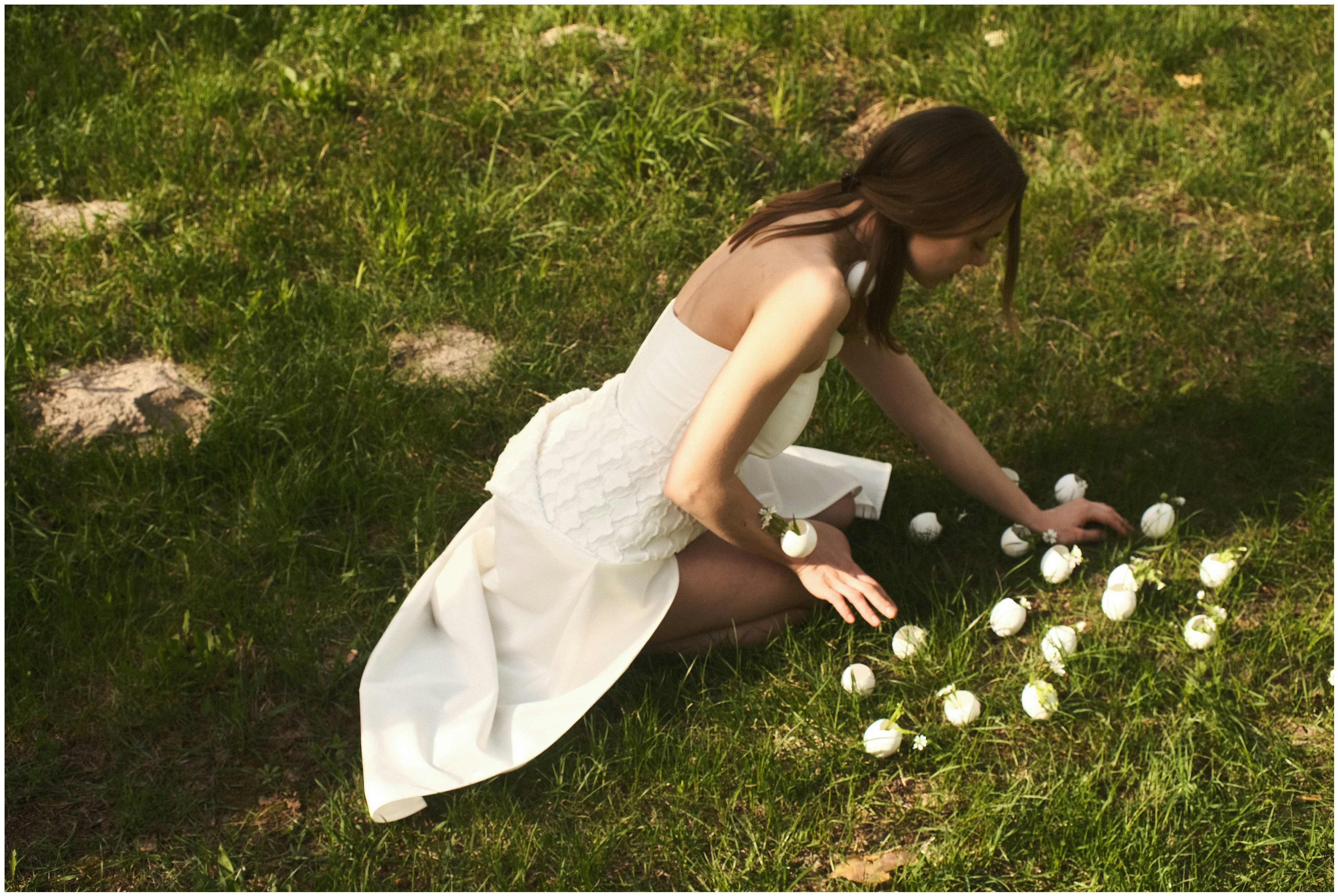 a woman in a white dress sitting on the grass