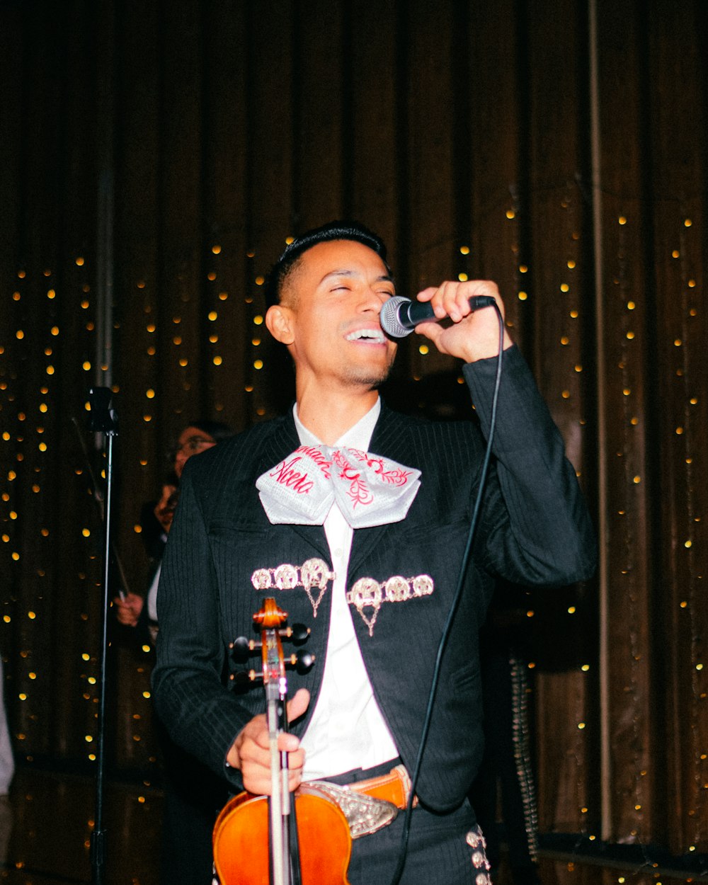 a man singing into a microphone while holding a violin