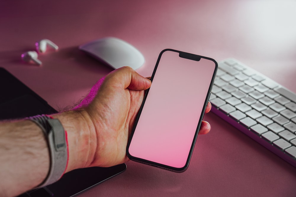 a person holding a phone in front of a keyboard