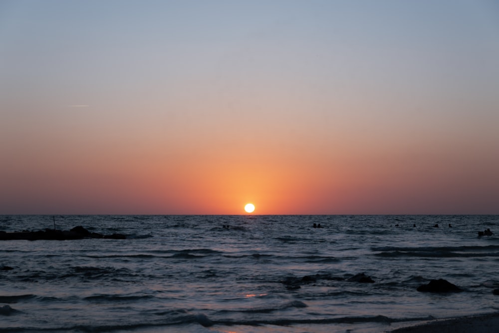 the sun is setting over the ocean on a clear day