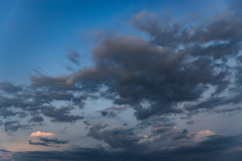 a plane flying through a cloudy blue sky