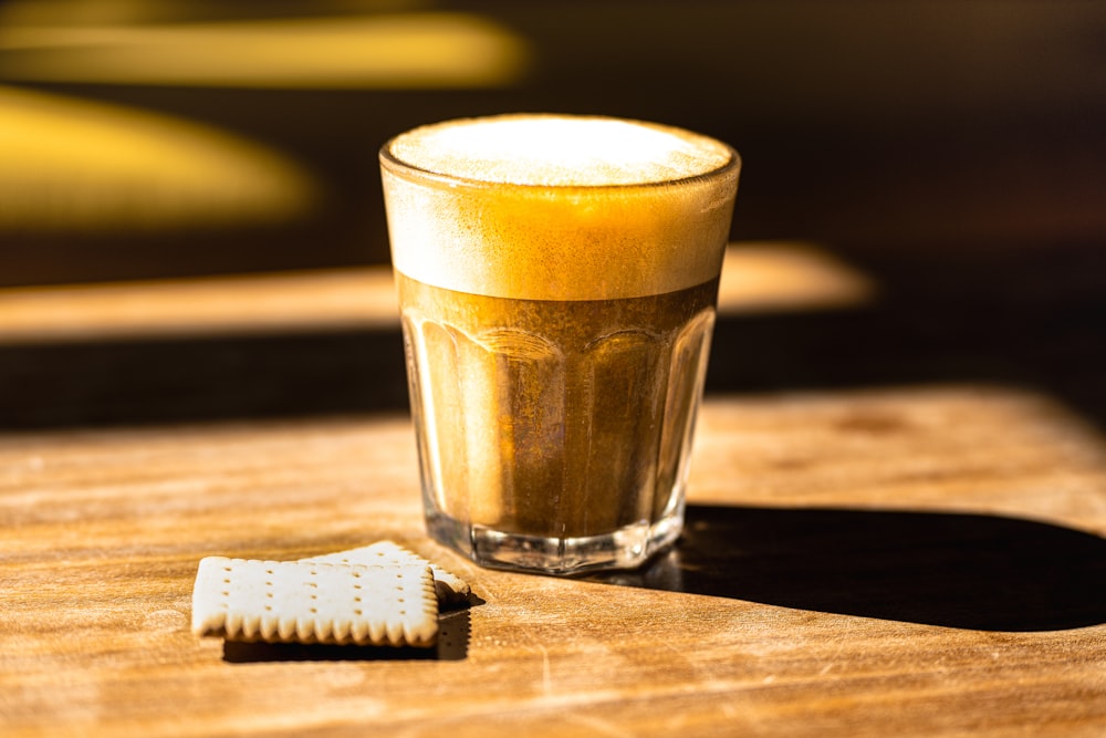 a glass of beer next to a white cookie