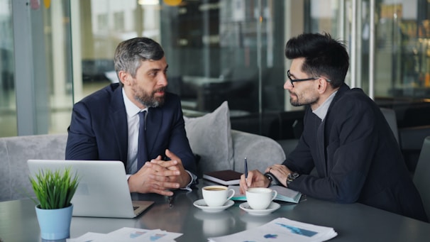 two men sitting at a table having a conversation