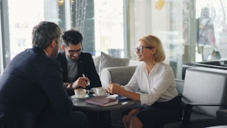two men and a woman sitting at a table having a conversation