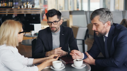 three people sitting at a table having a conversation