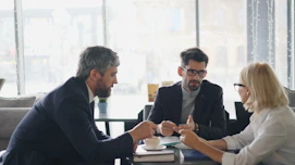 a group of people sitting around a table talking