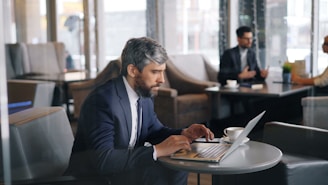 a man sitting at a table using a laptop computer