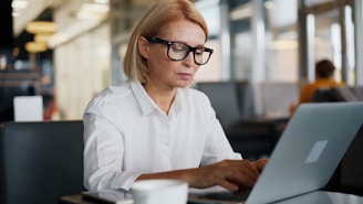 a woman sitting at a table using a laptop computer