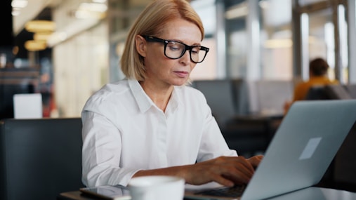 a woman sitting at a table using a laptop computer