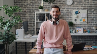 a man wearing headphones standing in front of a desk
