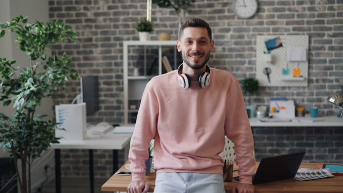 a man wearing headphones standing in front of a desk
