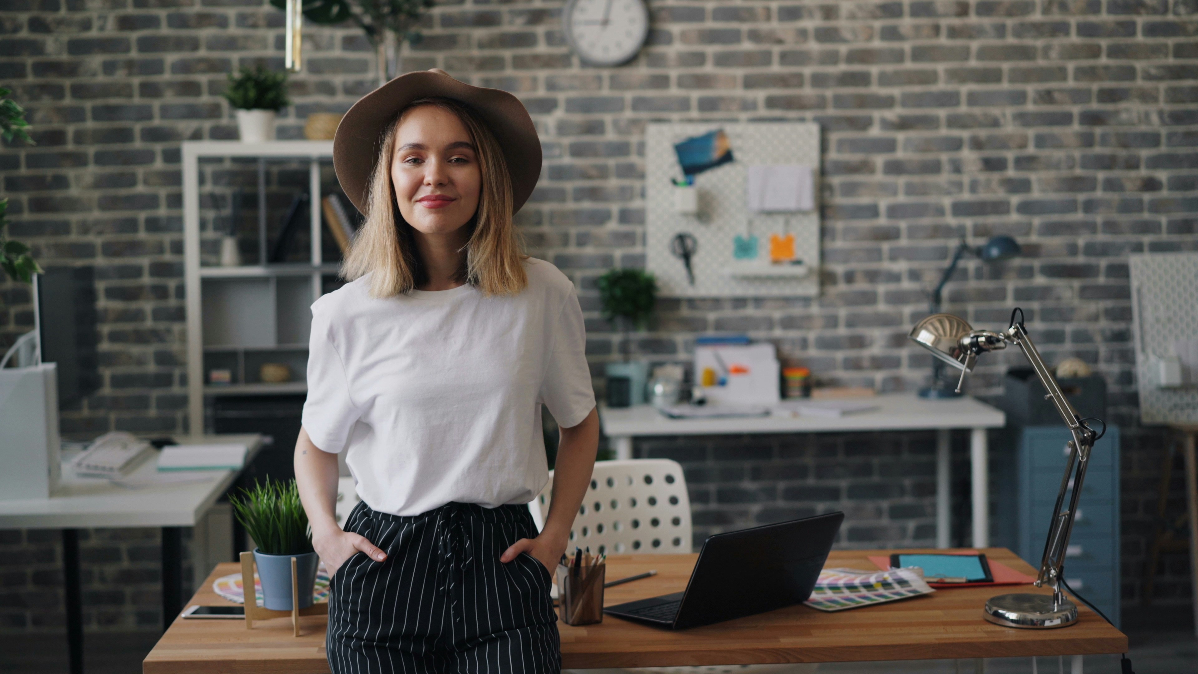 a woman standing in front of a desk with a laptop