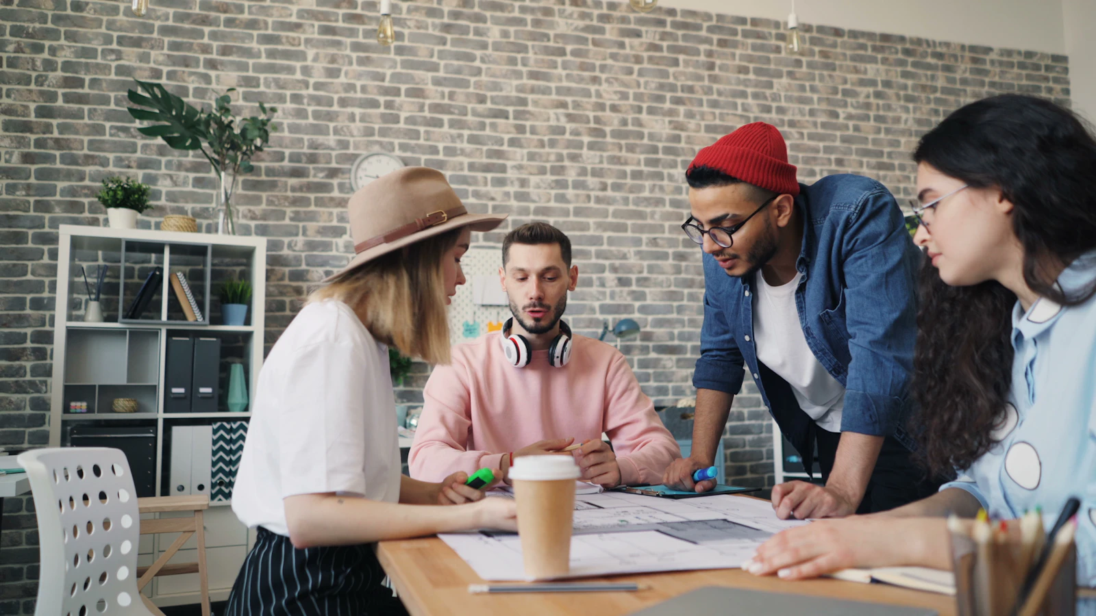 A group working through paperwork together at a table in a brick-walled office
