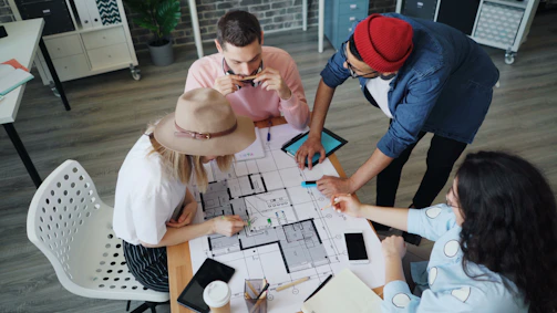 a group of people sitting around a table working on a project