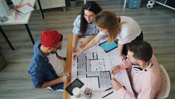 a group of people sitting around a table working on a project