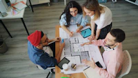 a group of people sitting around a table working on a project