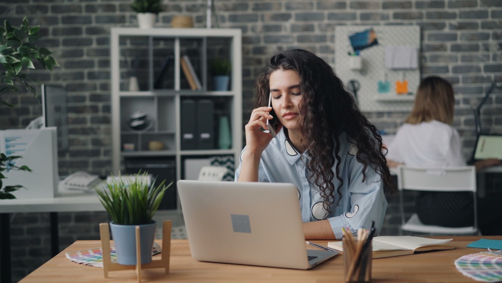 a woman sitting at a desk talking on a cell phone