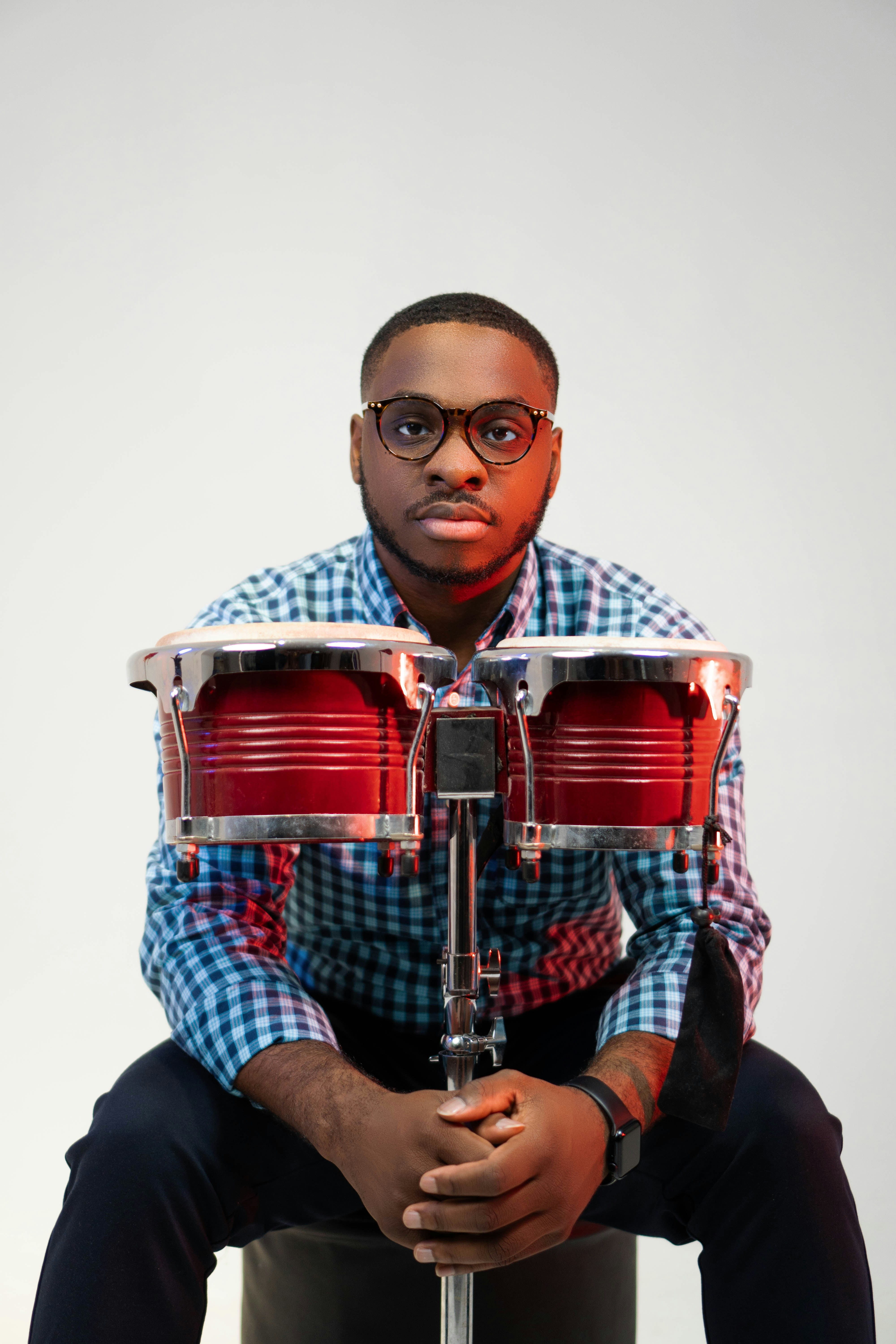 a man sitting on top of a stool holding a red drum