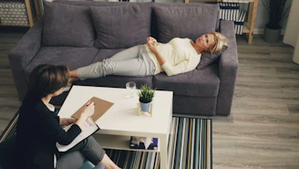 a woman laying on a couch next to another woman