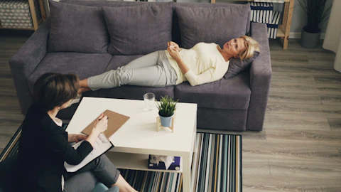 a woman laying on a couch next to another woman