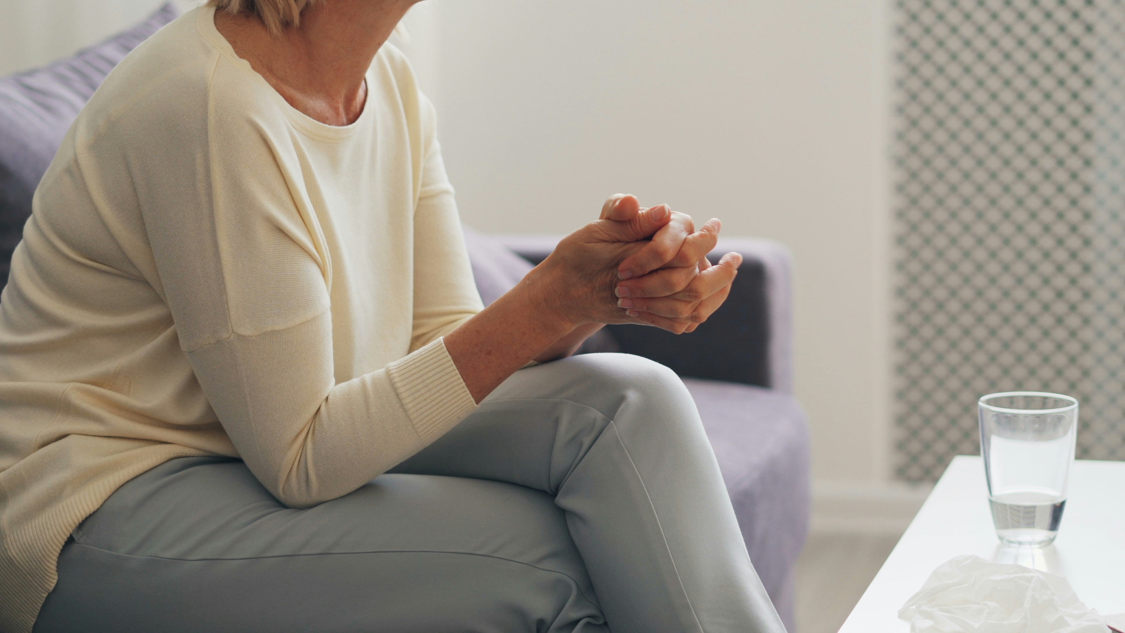a woman sitting on a couch holding her hands together