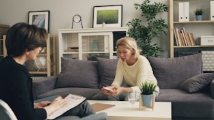 a woman sitting on a couch talking to another woman