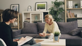 a woman sitting on a couch talking to another woman