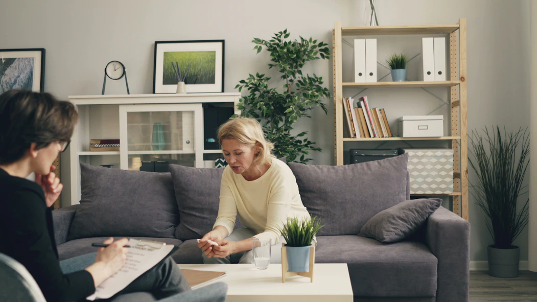 a woman sitting on a couch talking to another woman