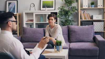 a man sitting on a couch talking to a woman
