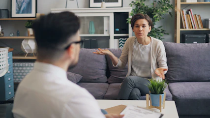 a woman sitting on a couch talking to a man