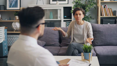a woman sitting on a couch talking to a man