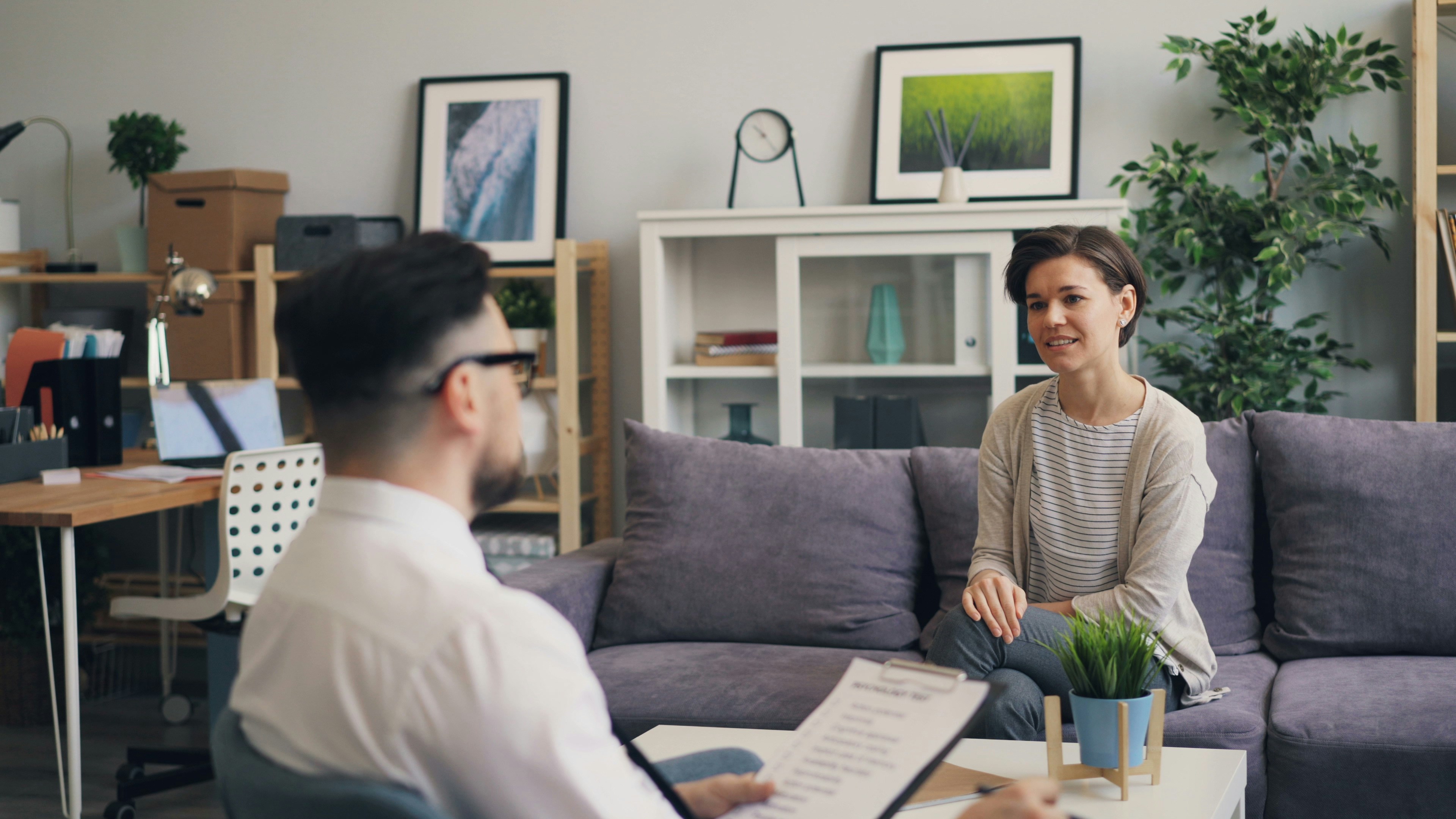 a woman sitting on a couch talking to a man