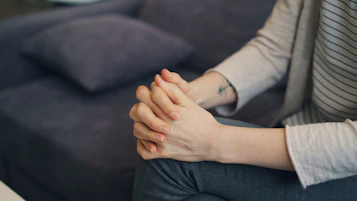 a woman sitting on a couch holding her hands together