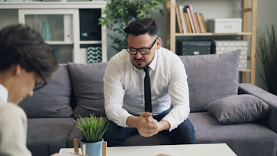 a man sitting on a couch in front of a woman