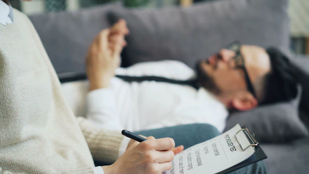 a person laying on a couch writing on a piece of paper