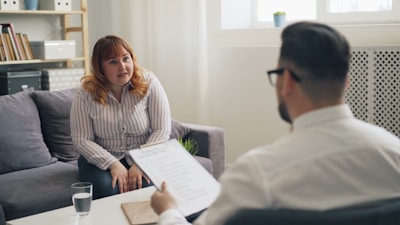 a woman sitting on a couch talking to a man