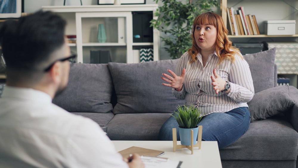 a woman sitting on a couch talking to a man